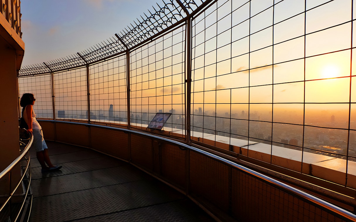 Baiyoke Sky Hotel observation deck view at sunset, Bangkok skyline in background.