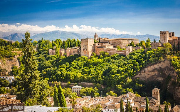 Alhambra palace and fortress complex in Granada, Spain, surrounded by lush greenery.