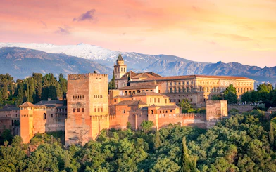 Alhambra palace with Sierra Nevada mountains at sunset, viewed from Malaga tour.