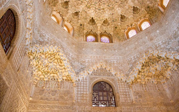 Alhambra's intricate stucco ceiling and arches on guided tour from Malaga.