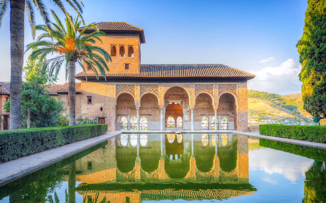 Alhambra palace reflecting in a tranquil pool during a guided tour from Malaga.