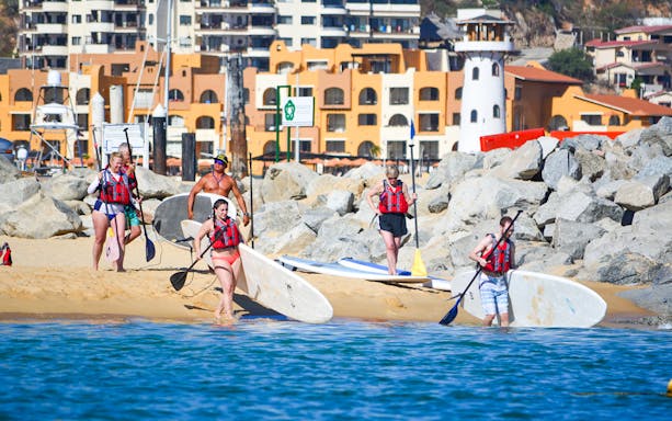 Group preparing for paddleboarding at Cabo San Lucas beach, near the Arch.