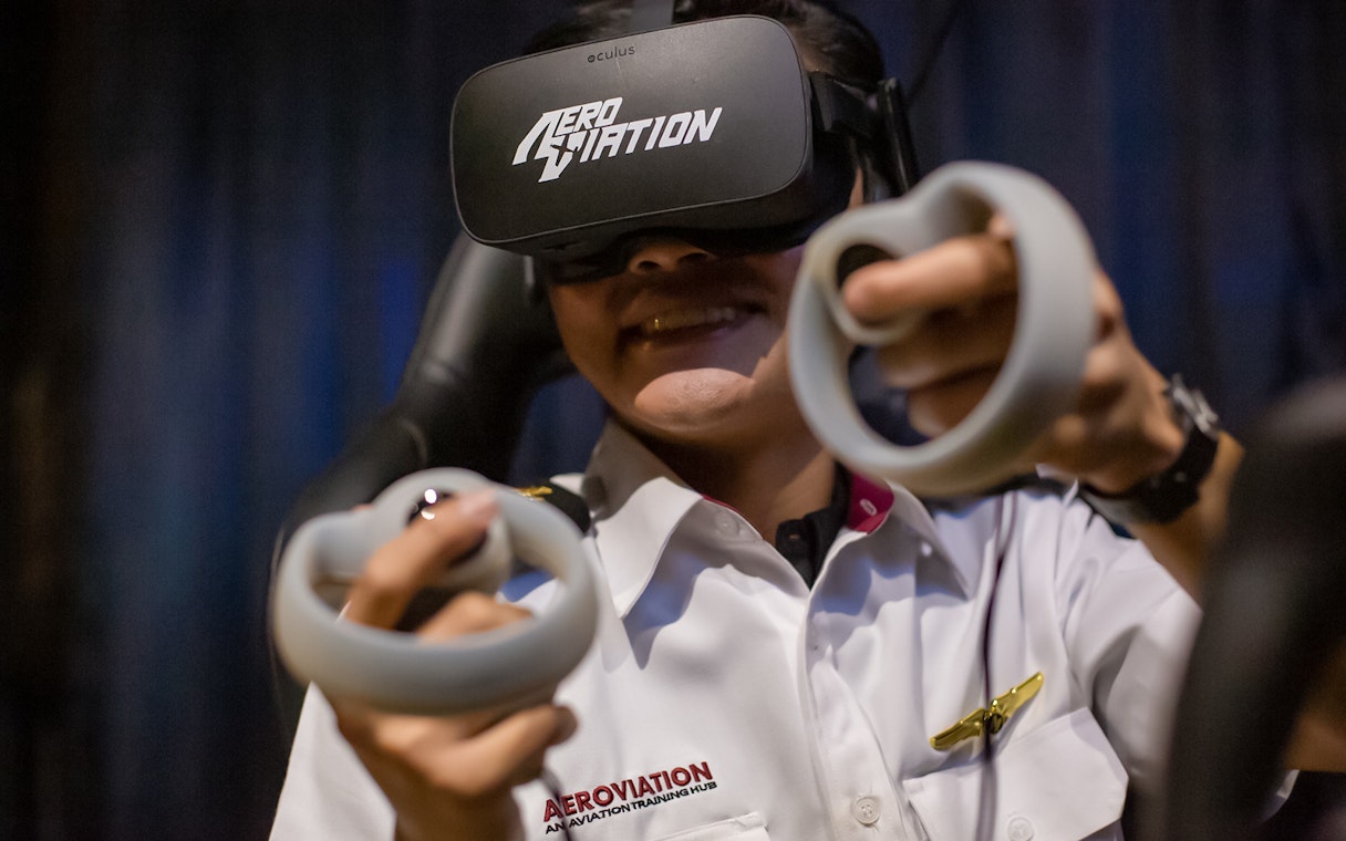 Person using virtual reality headset and controllers at Aeroviation flight experience.