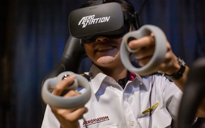 Person using virtual reality headset and controllers at Aeroviation flight experience.