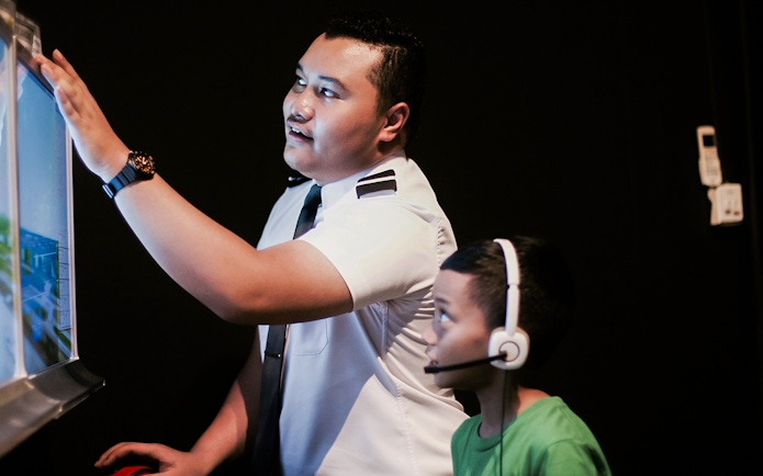 Pilot guiding child in flight simulator during Aeroviation Full Flight Experience.