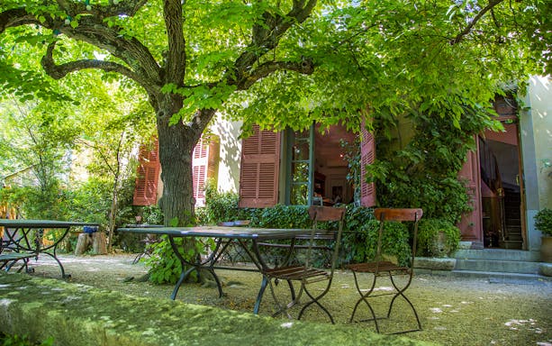 Outdoor seating area under trees at L'Atelier des Lumières, Paris.