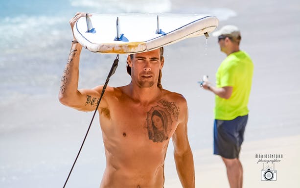 Surfer carrying board on Costa Azul beach during private Los Cabos surf lesson.