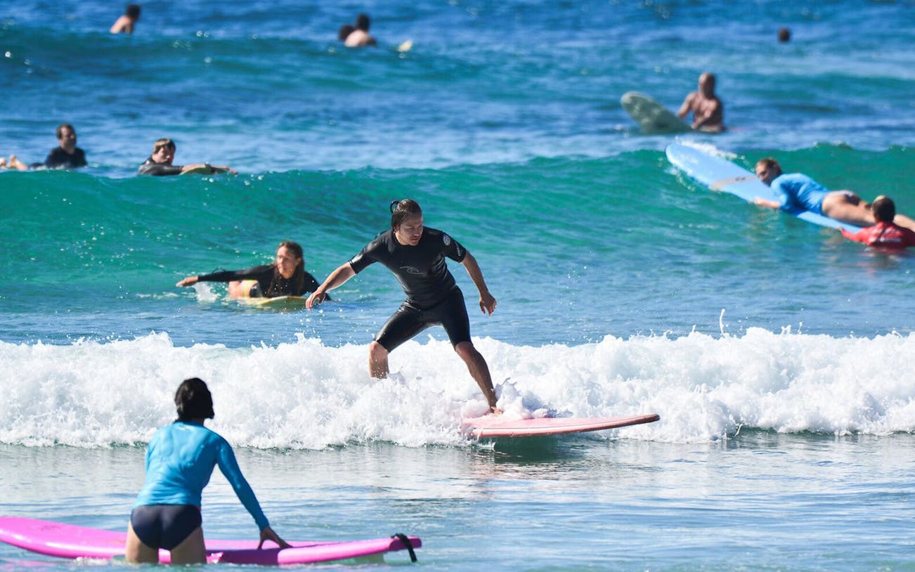 Surfers taking private lessons at Cerritos beach, riding waves in the ocean.