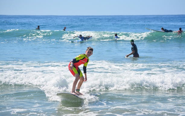 Young surfer riding a wave during a private lesson at Cerritos Beach.