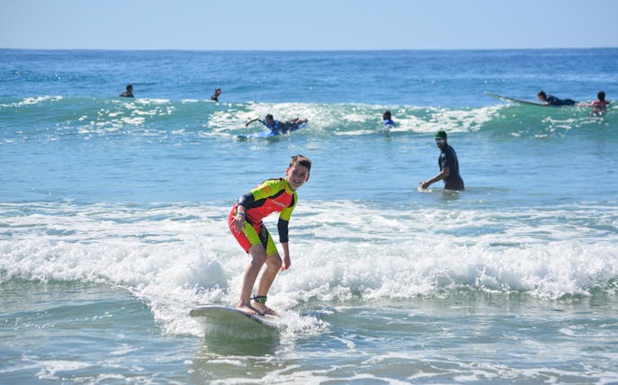 Young surfer riding a wave during a private lesson at Cerritos Beach.