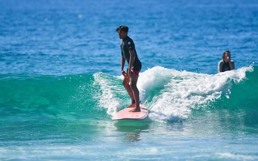 Surfer riding a wave during a private lesson at Cerritos Beach.