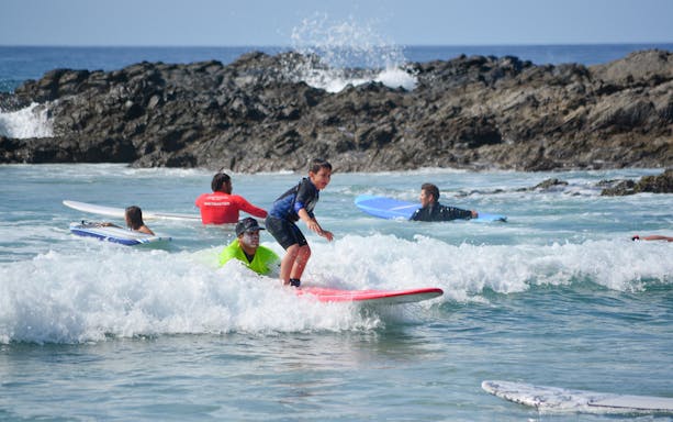 Young surfer learning with instructor at Cerritos beach.
