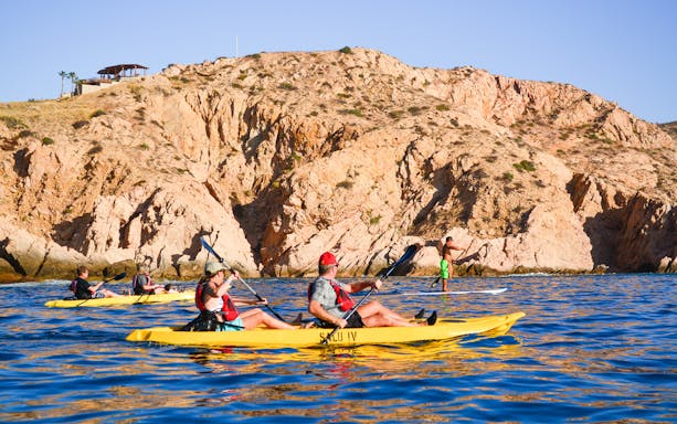 Kayakers paddling near rocky cliffs on Cabo San Lucas Glass Bottom Kayak Tour.