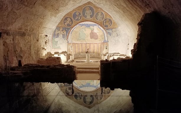 Underground frescoes in Narni Pass, Italy, depicting religious figures in an ancient stone chamber.