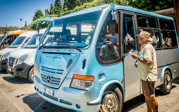 Tourists boarding a blue shuttle bus for Capri and Anacapri tour from Sorrento.