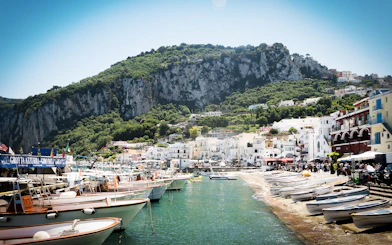 Boats docked at Marina Grande, Capri with cliffs and hillside buildings in the background.