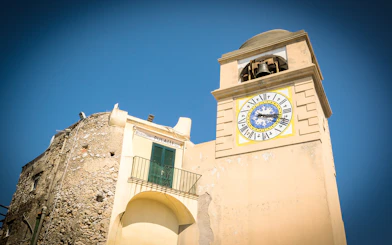Clock tower in Capri, Italy, with Roman numerals and bell, part of Capri & Anacapri tour.