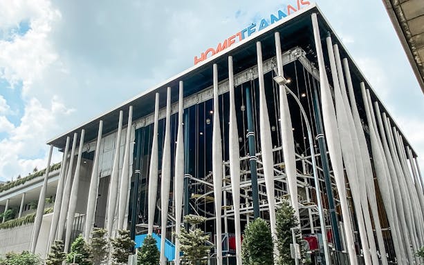 Modern building facade of Adventure HQ with vertical columns and greenery.