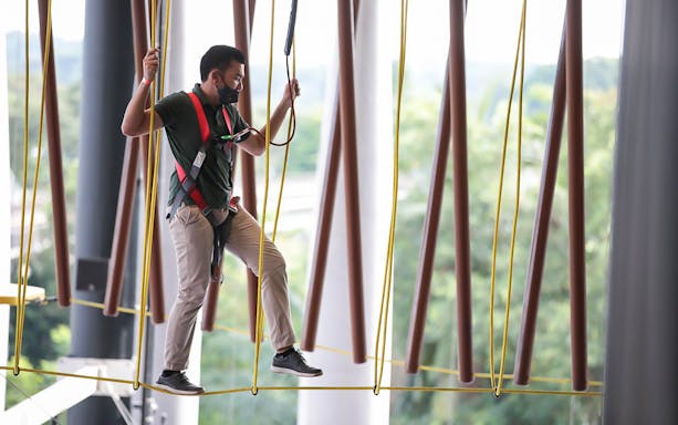 Man navigating ropes course at Adventure HQ with safety harness.