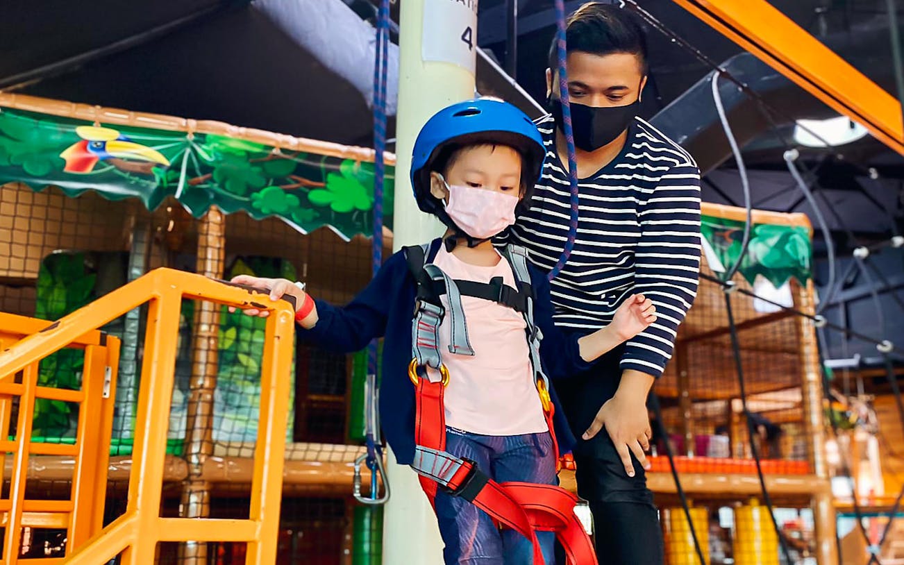 Child in harness at Waka Waka Safari-themed indoor playground.