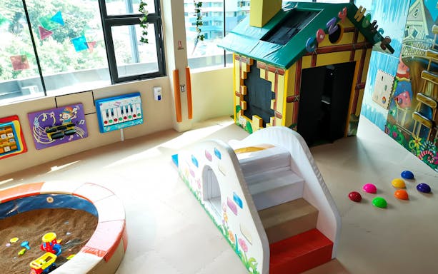 Indoor playground with safari-themed playhouse, slide, and musical wall games at Waka Waka.