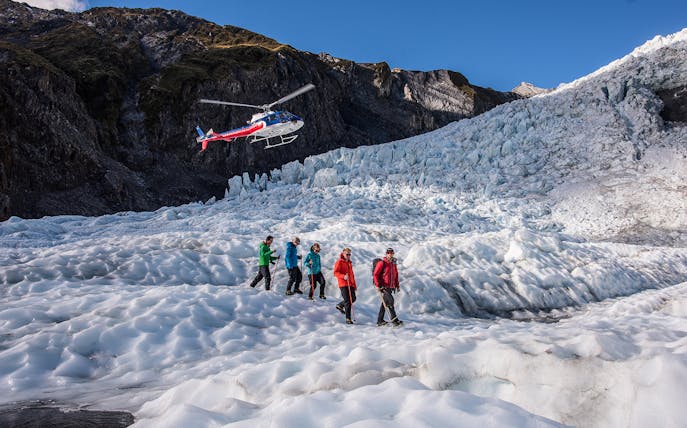 Helicopter and hikers on Franz Josef Glacier during expert guided heli-hike tour.