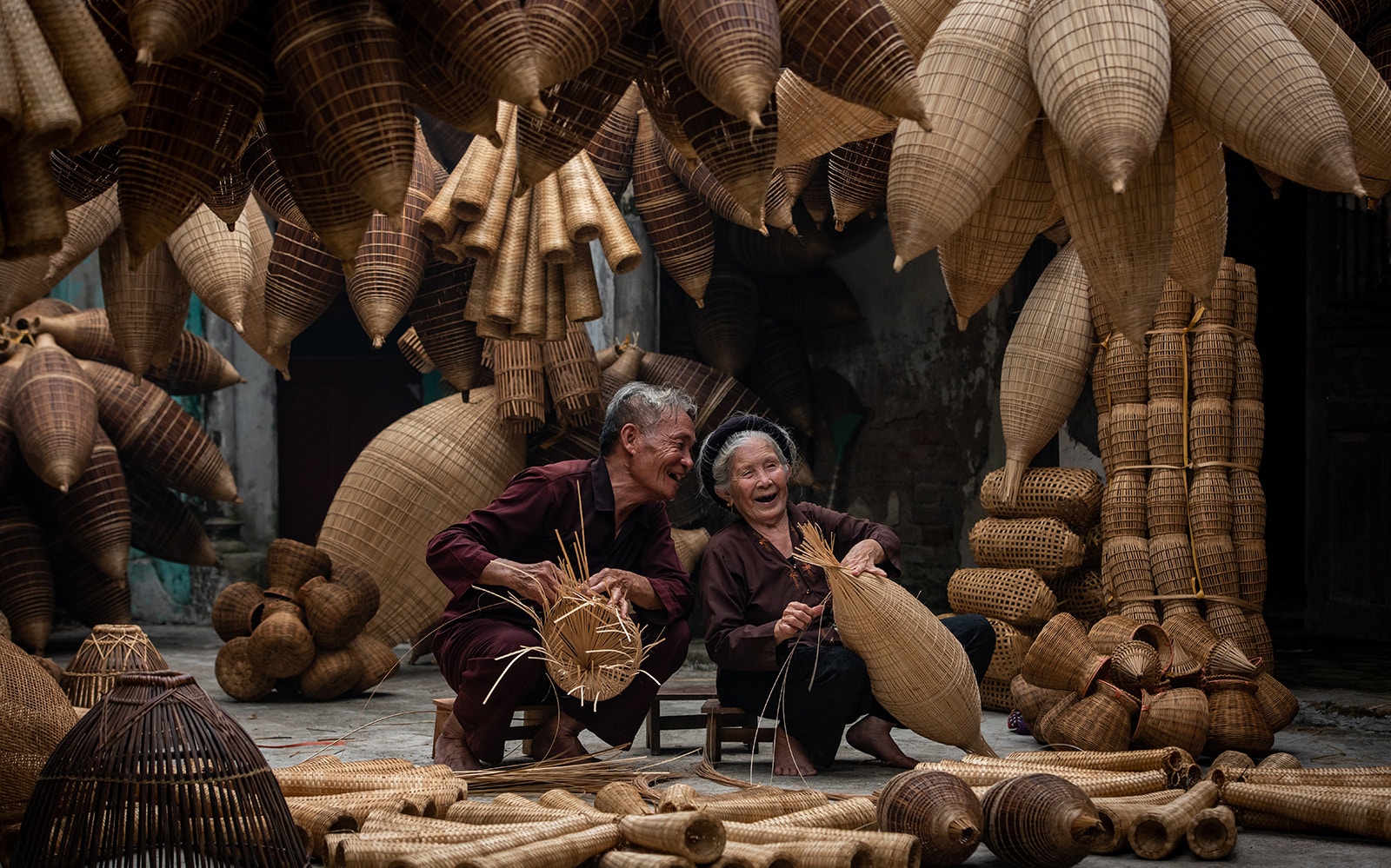 Elderly couple weaving baskets in a traditional Hmong village during a half-day tour of Doi Suthep.