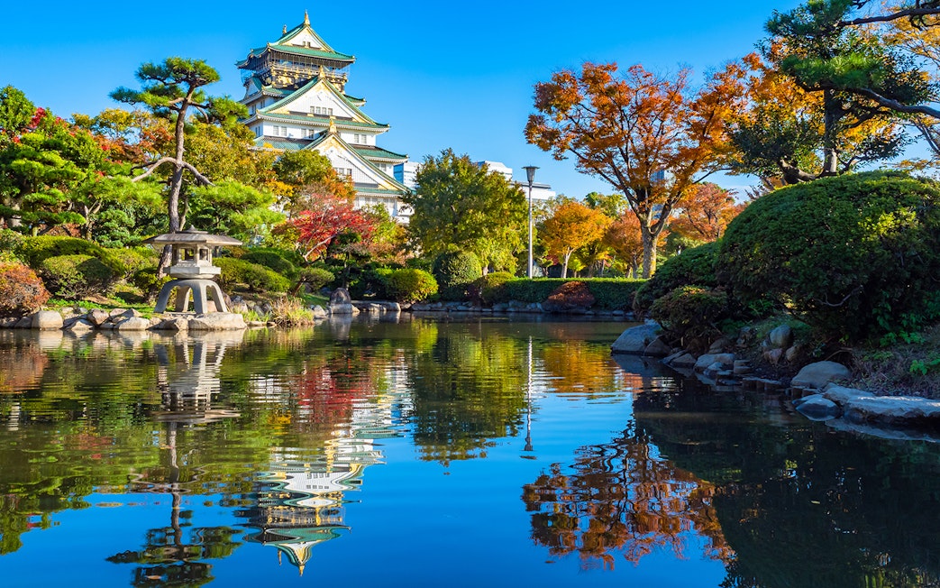Osaka Castle gardens in spring with pond reflection, view from park, Japan.
