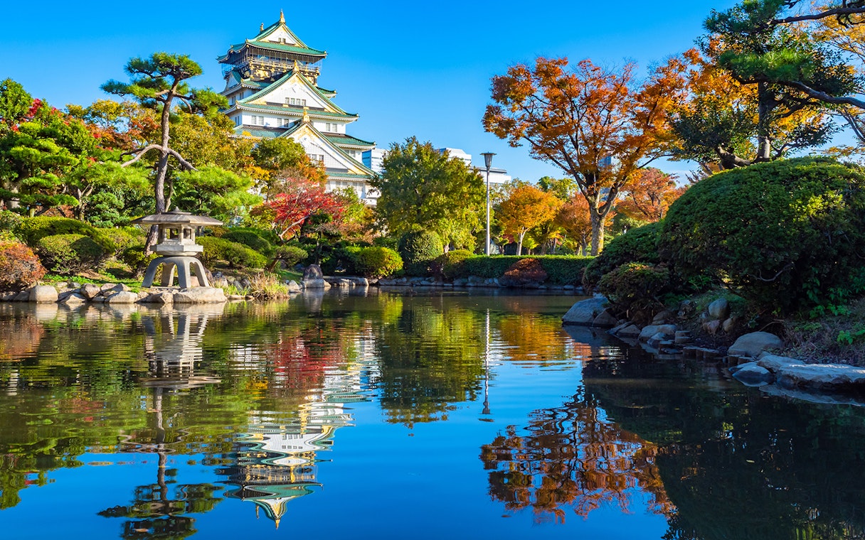Osaka Castle gardens in spring with pond reflection, view from park, Japan.
