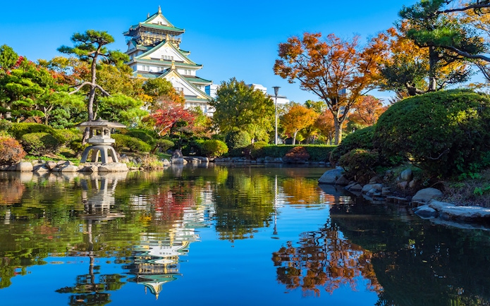 Osaka Castle gardens in spring with pond reflection, view from park, Japan.