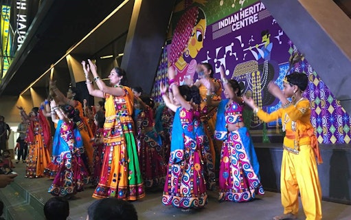 Traditional dance performance at Indian Heritage Centre, featuring colorful attire and cultural backdrop.