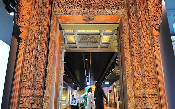 Ornate wooden entrance at Indian Heritage Centre, showcasing intricate carvings and cultural exhibits inside.