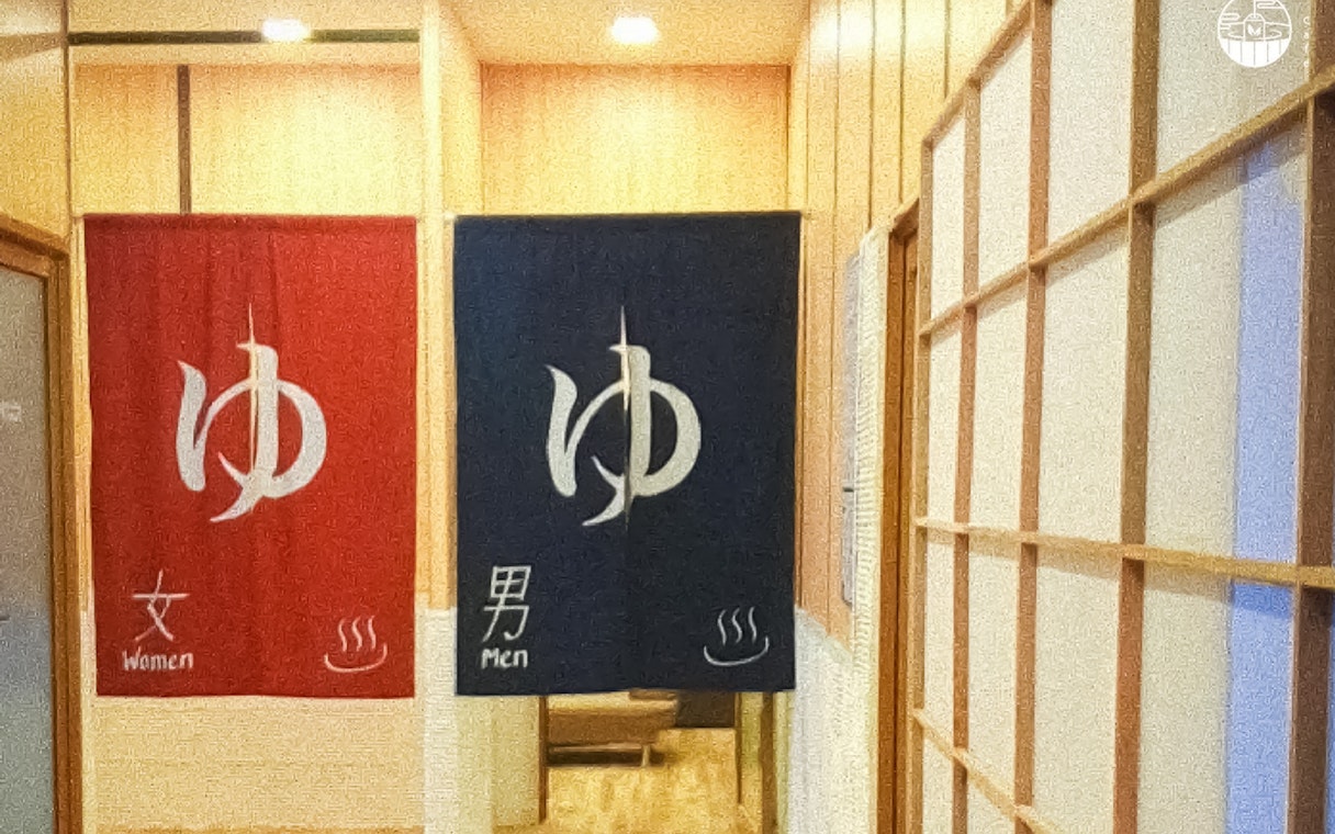 Red and blue curtains at Joya Onsen Cafe in Singapore, marking entrances for women and men.