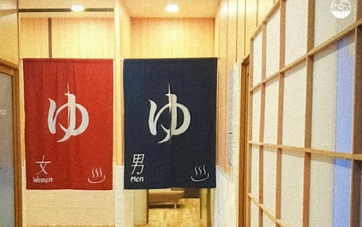 Red and blue curtains at Joya Onsen Cafe in Singapore, marking entrances for women and men.