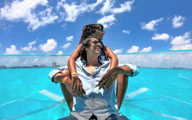Tourists on a clear boat exploring Nichupte Lagoon in Cancun, Mexico.