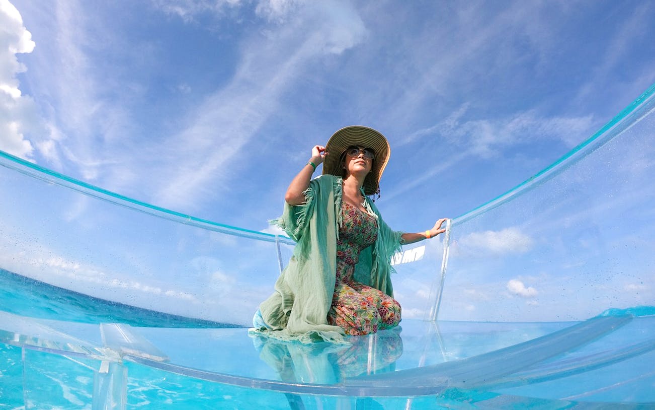 Tourists on a clear boat exploring Nichupte Lagoon in Cancun, Mexico.