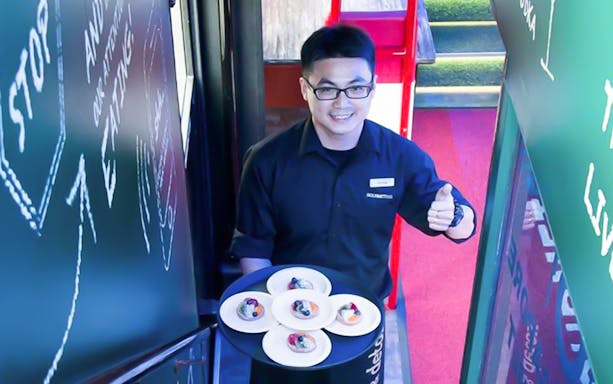 Server presenting dishes on Singapore GOURMETbus Michelin Bib Gourmand tour.