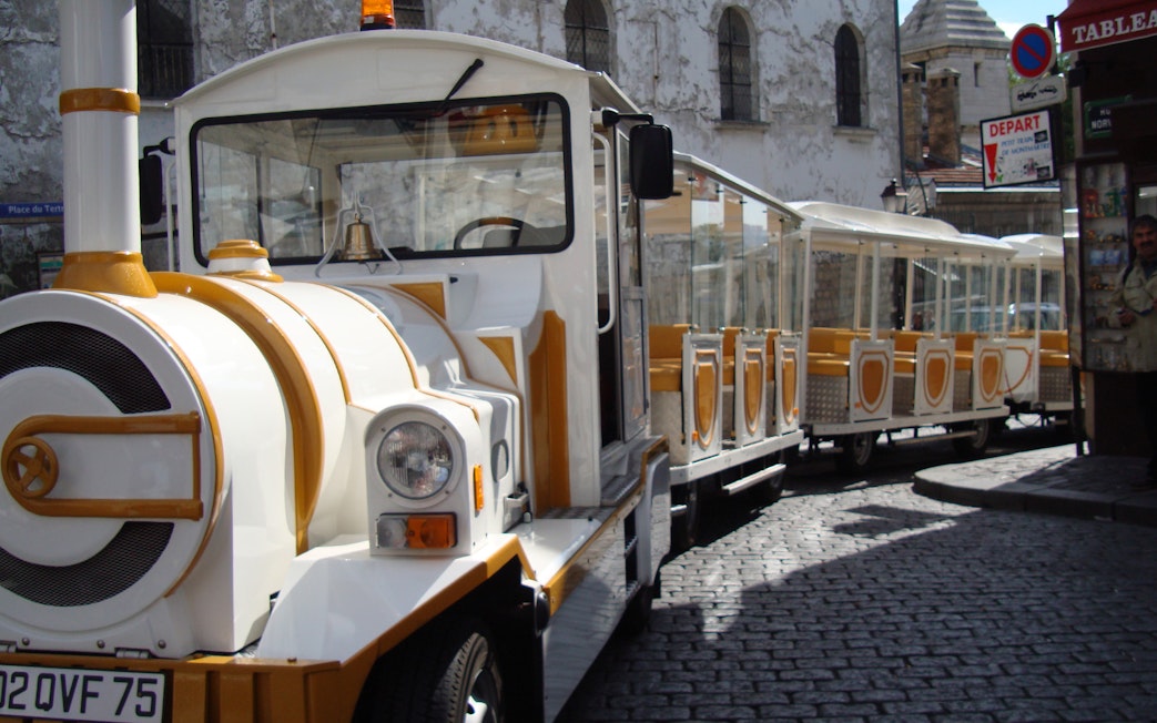 Tourist train on cobblestone street in Montmartre, Paris.