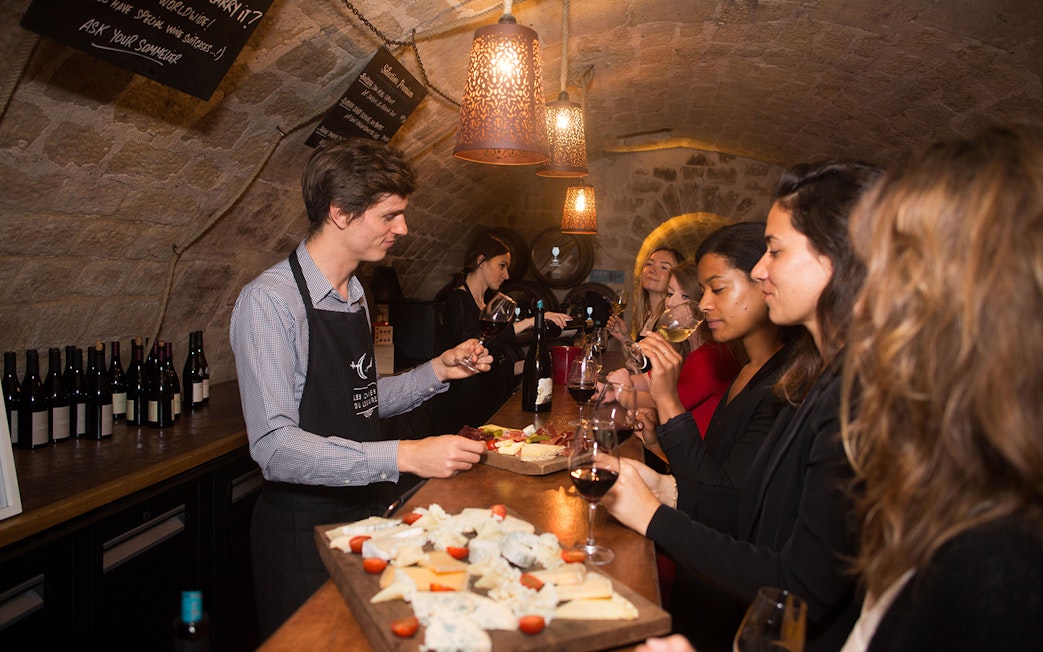 Wine tasting experience in a Parisian cellar with a group sampling cheese and wine.