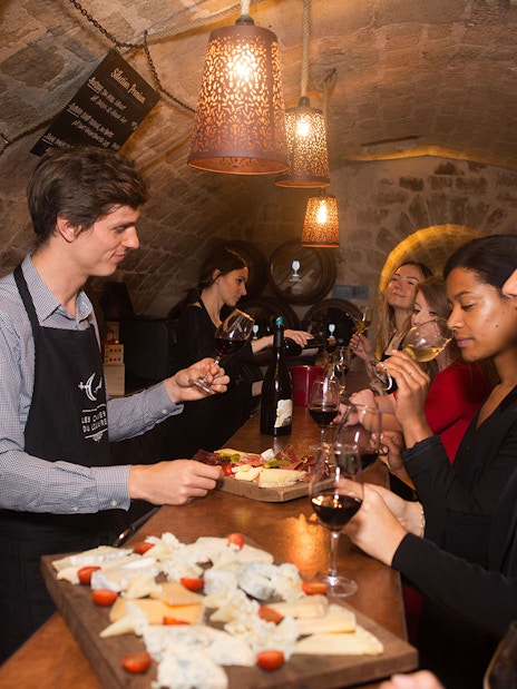 Wine tasting experience in a Parisian cellar with a group sampling cheese and wine.