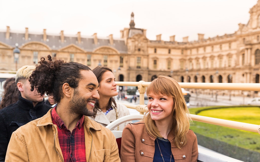 Tourists on an open-top bus near the Louvre Museum in Paris.