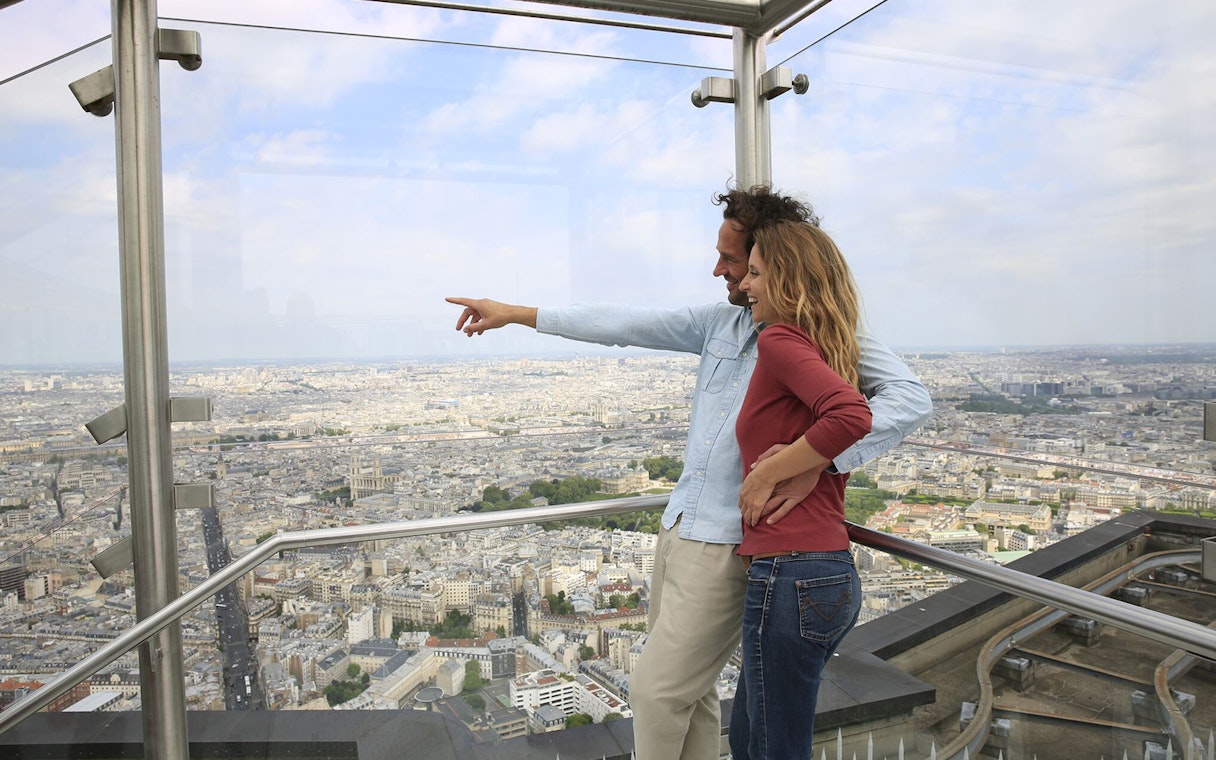 Couple enjoying panoramic view of Paris from Montparnasse Tower observation deck.