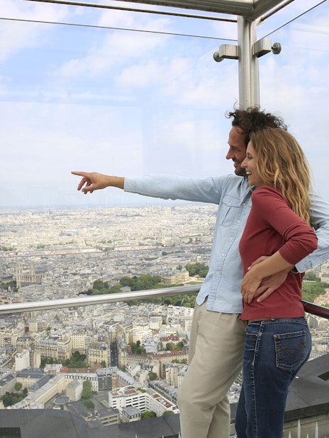 Couple enjoying panoramic view of Paris from Montparnasse Tower observation deck.