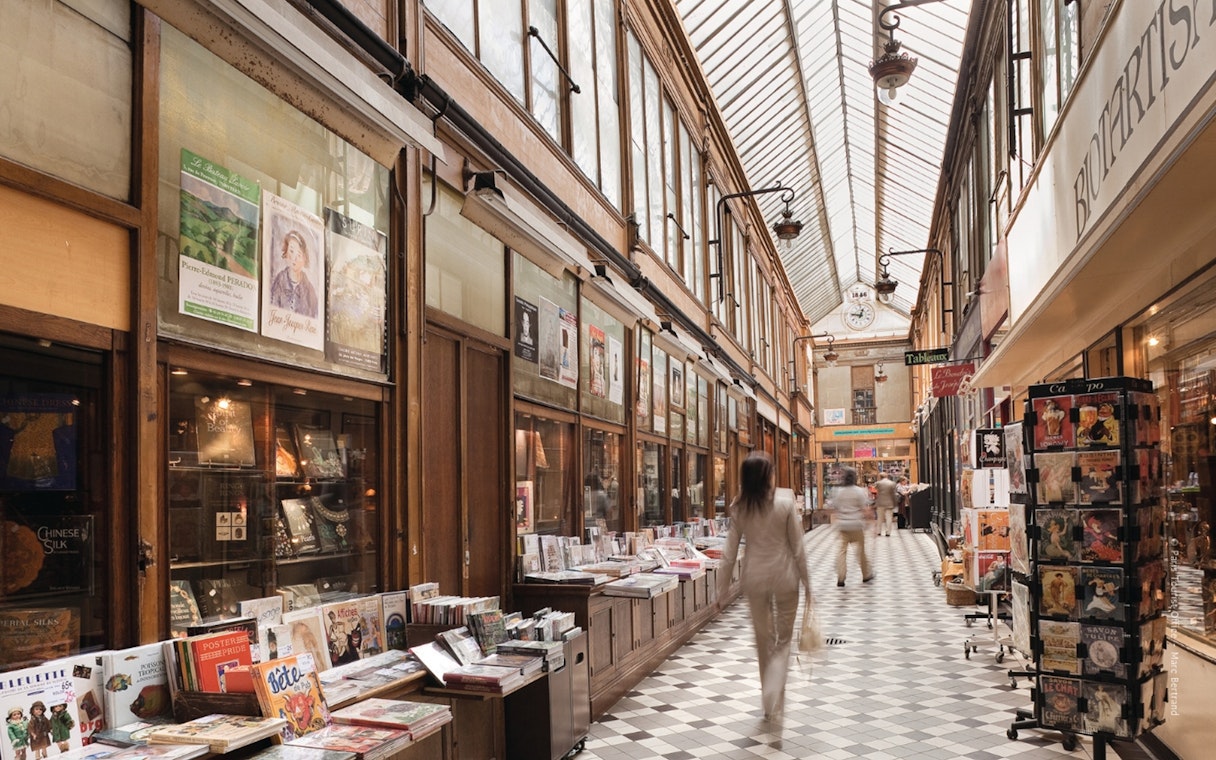 Covered passageway in Paris with shops and people walking, part of The Paris Pass attractions.