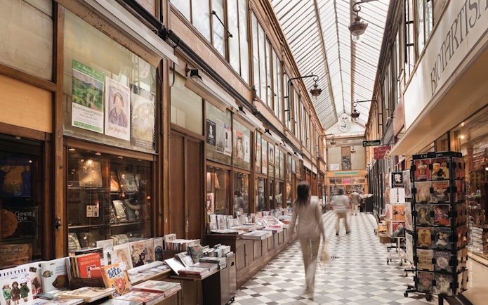 Covered passageway in Paris with shops and people walking, part of The Paris Pass attractions.