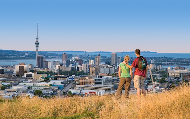 Couple overlooking Auckland skyline with Sky Tower in view.