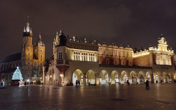 Krakow's Main Square at night with St. Mary's Basilica and Cloth Hall illuminated.