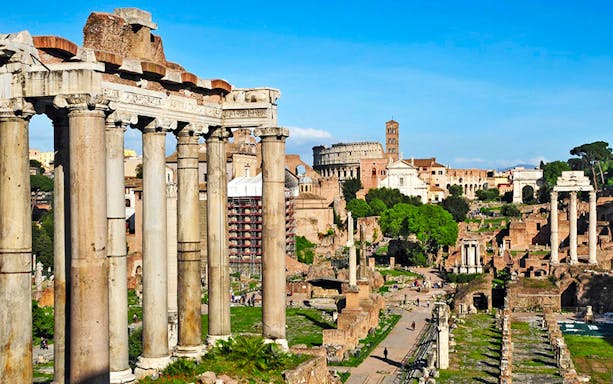 Ancient Roman Forum ruins with Colosseum in background, Rome scooter tour.