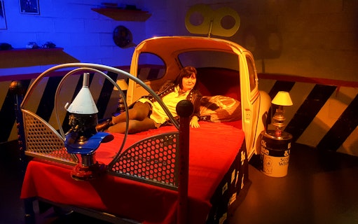 Person relaxing on a car-themed bed at the Torino Car Museum.
