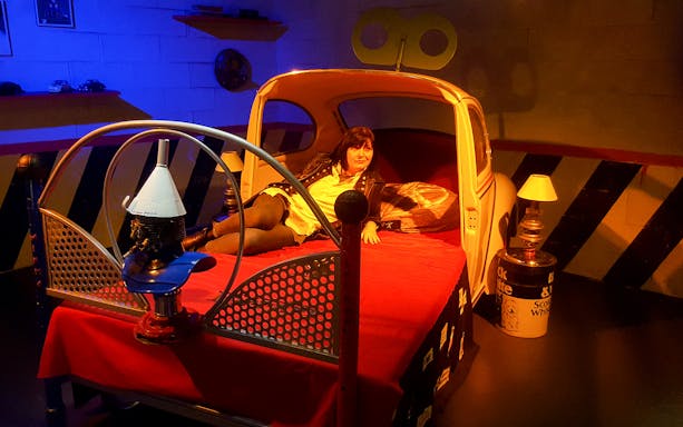 Person relaxing on a car-themed bed at the Torino Car Museum.